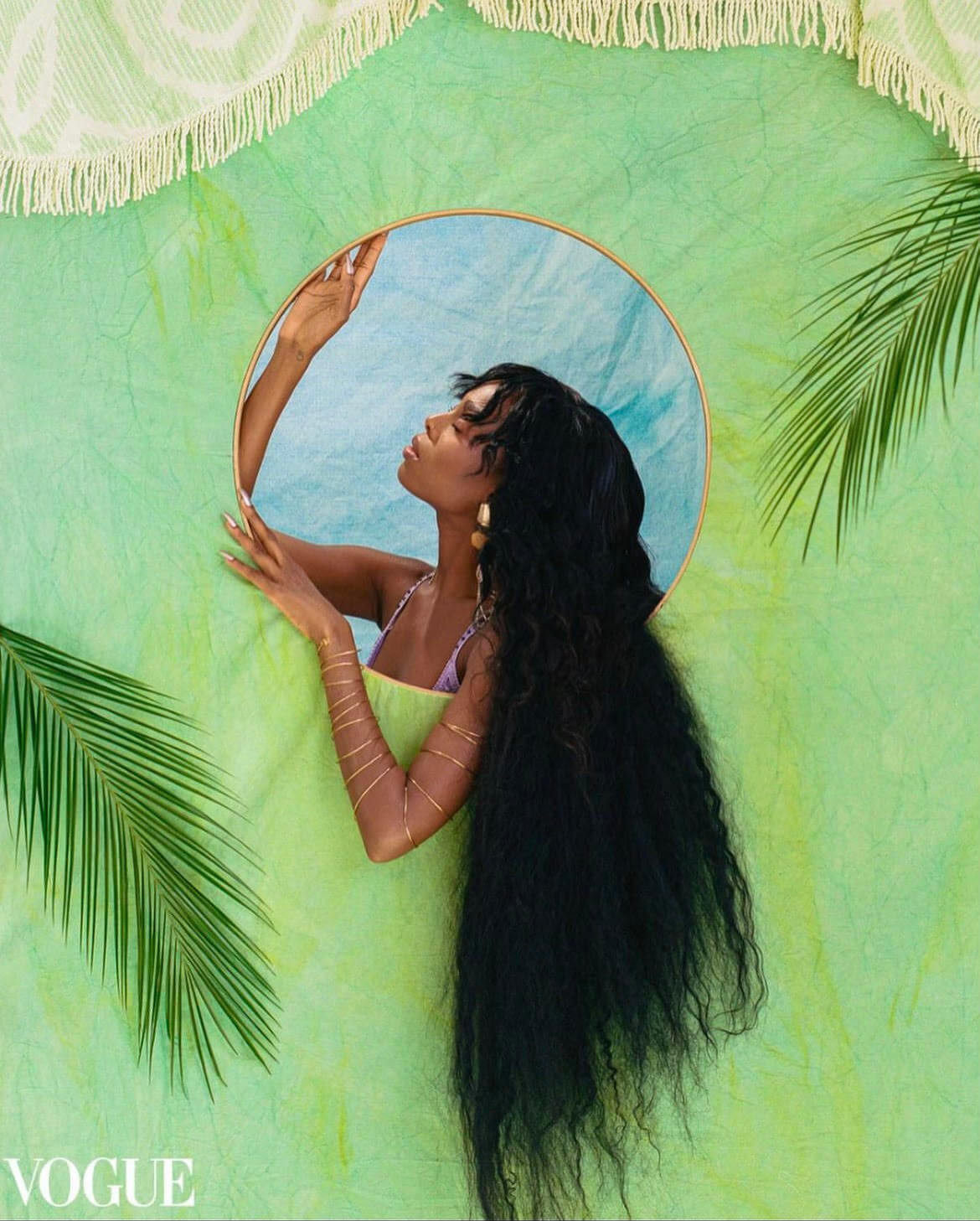 Beautiful black woman with long wavy hair against a pastel green backdrop